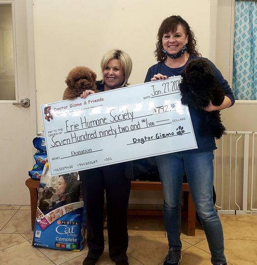 Two women holding Gizmo and Gadget the dogs and a donation check for the Erie Humane Society 