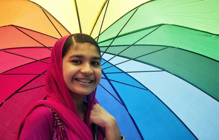 A young girl holding a rainbow umbrella