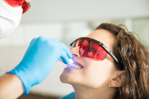 female patient receiving whitening treatment in dental office cosmetic dentistry results sleep dentistry erie