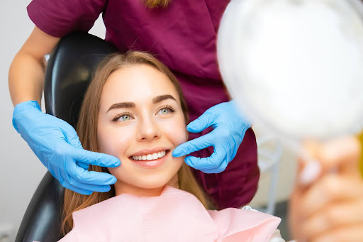 female patient smiling and looking at new teeth with mirror cosmetic dentistry results sleep dentistry erie
