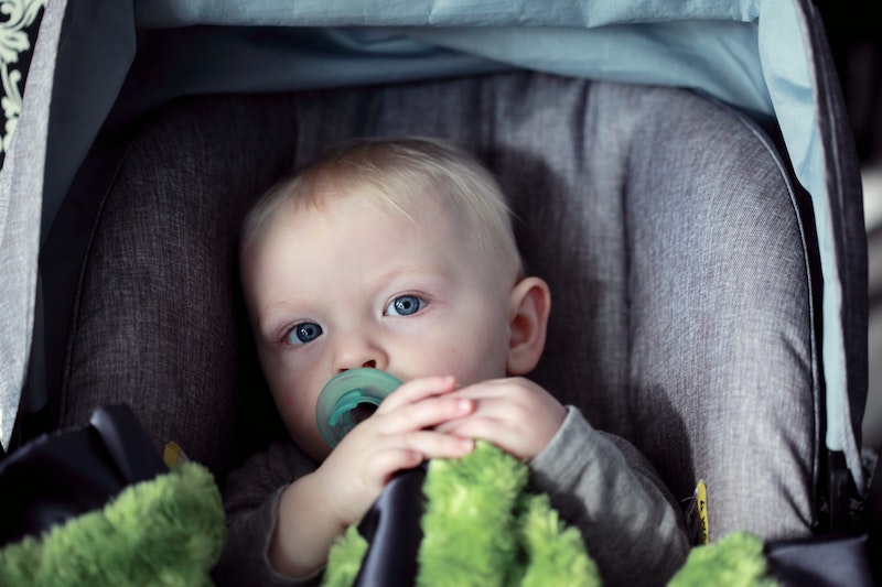 A child in a stroller with a pacifier in their mouth